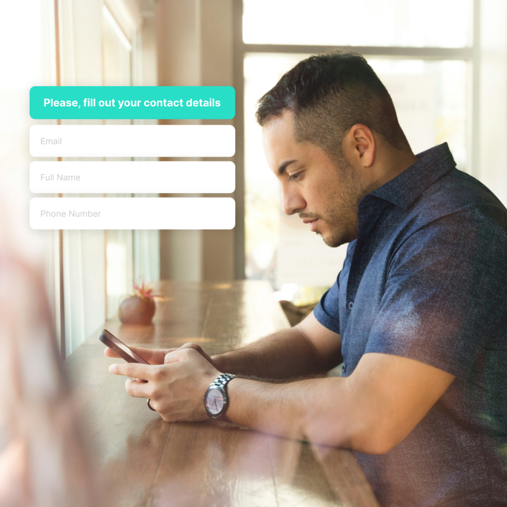 Man sitting at a table looking at his phone, next to a form asking for contact details including email, full name, and phone number.